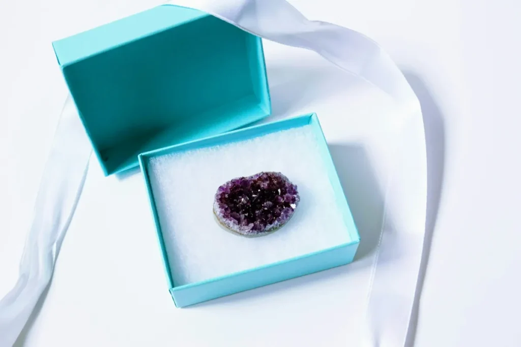 Coffret cadeau ouvert contenant une druse d'améthyste